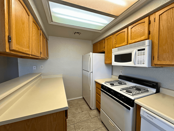 Santa Teresa apartment for rent - A kitchen with wooden cabinets and white appliances.