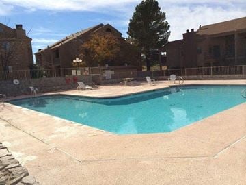 El Paso apartment for rent - A swimming pool surrounded by a stone wall and a fence.