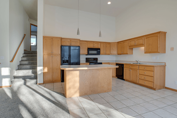 Fargo townhouse for rent - A kitchen with wooden cabinets and a black fridge.