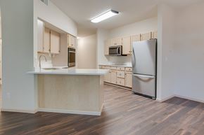 Fargo apartment for rent - A kitchen with wooden floors and a white refrigerator. at Eighth Street Manor Apartments, Fargo, ND, 58103