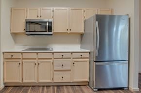 Fargo apartment for rent - A kitchen with a stainless steel refrigerator and wooden cabinets. at Eighth Street Manor  Apartments, Fargo, ND