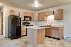 Fargo apartment for rent - a kitchen with wooden cabinets and a black refrigerator at Augusta  Apartments, Fargo, ND
