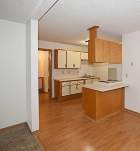 Hudson apartment for rent - an empty kitchen and living room with wood flooring and wooden cabinets at Aspen Apartments, Hudson, WI, 54016