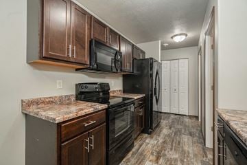 Sioux Falls townhouse for rent - the kitchen of a home with black appliances and granite counter tops