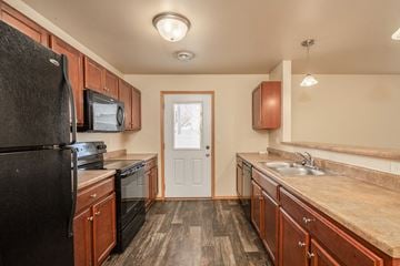 Sioux Falls townhouse for rent - a kitchen with black appliances and wooden cabinets