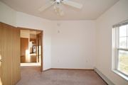 Clearwater apartment for rent - an empty living room with a ceiling fan and a door to a hallway at Cedar Ridge  Apartments, Clearwater, MN