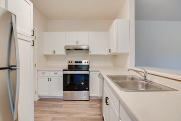 Fargo apartment for rent - A kitchen with white cabinets and a stainless steel refrigerator.