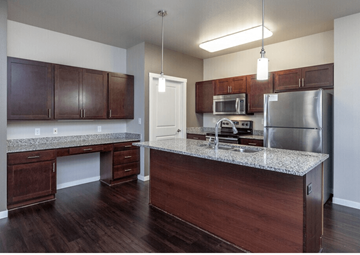 West Fargo apartment for rent - A kitchen with dark wood cabinets and a granite countertop.