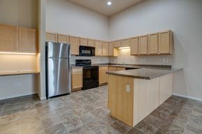 West Fargo apartment for rent - A kitchen with wooden cabinets and a granite countertop.