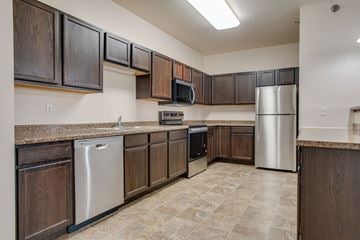 West Fargo apartment for rent - A kitchen with brown cabinets and a stainless steel refrigerator.