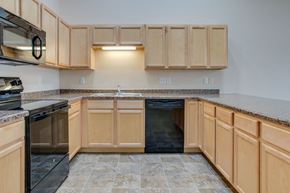 West Fargo apartment for rent - A kitchen with wooden cabinets and a black dishwasher.
