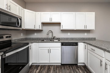 Fargo apartment for rent - A kitchen with white cabinets and a black stove top oven.