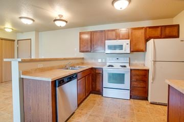 Moorhead apartment for rent - a kitchen with white appliances and wooden cabinets
