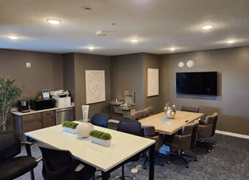 A conference room with tables and chairs and a tv