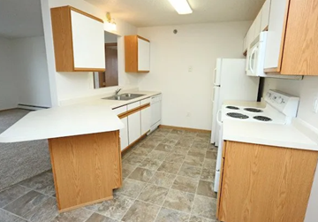 West Fargo apartment for rent - A kitchen with white appliances and wooden cabinets.