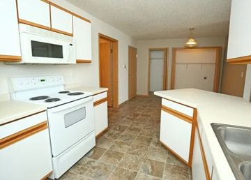 West Fargo apartment for rent - A kitchen with white appliances and brown cabinets.