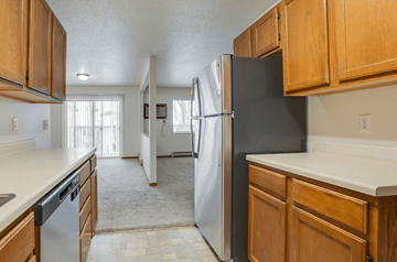 Fargo apartment for rent - A kitchen with a black refrigerator and wooden cabinets.