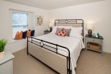 Phoenixville apartment for rent - A bedroom with a large bed and a nightstand with a lamp.