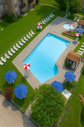 Feasterville apartment for rent - A pool surrounded by blue umbrellas and red and white striped umbrellas.