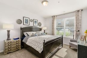 Columbus apartment for rent - A bedroom with a large bed, a nightstand, and a chair.