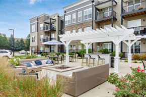 Columbus apartment for rent - A patio with a white pergola and a planter box is surrounded by apartment buildings.