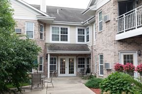 Mequon apartment for rent - the front entrance of a building with a sidewalk and chairs