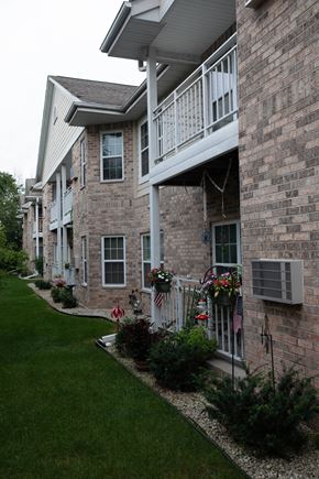 Mequon apartment for rent - a brick house with a balcony and a lawn