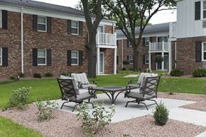 Cedarburg apartment for rent - a patio with two chairs and a table in front of an apartment building