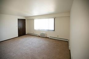 Grafton apartment for rent - A room with a brown carpet and a window with blinds.