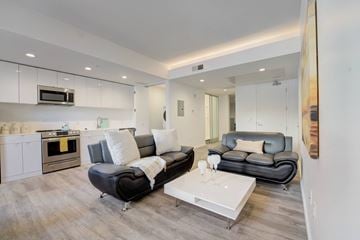 Cleveland apartment for rent - A modern living room with a black leather couch and a white coffee table.