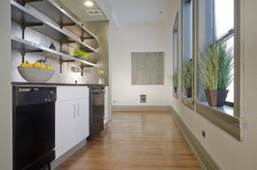 Seattle apartment for rent - a kitchen with white cabinets and a black stove and a window