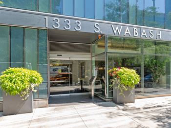 The front of a glass building with flowers in front of it