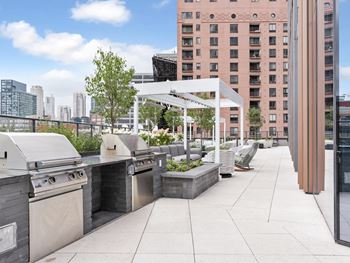 The outdoor patio of a building with barbecue grills and furniture