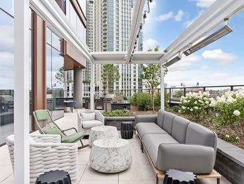 A living area with couches and chairs and a balcony with tall buildings