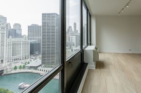 Chicago apartment for rent - A room with a large window overlooking a river and city buildings at Columbus Plaza, Chicago, Illinois