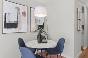 Detroit apartment for rent - a dining room with blue chairs and a white table with a lamp and paintings on at The Pavilion, Detroit, Michigan