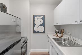 Detroit apartment for rent - kitchen with stainless steel appliances and white cabinets and a wall art of a white snake  at The Pavilion, Michigan, 48207