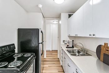 A kitchen with white cabinets and black appliances