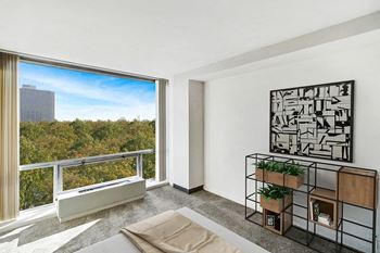 A bedroom with a large window and a balcony