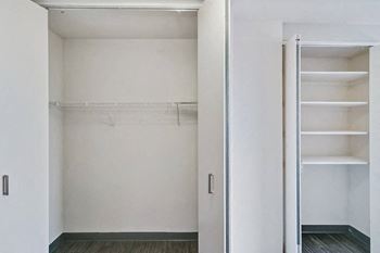 A walk in closet with white walls and a mirrored door
