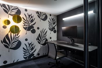 A modern office with a leaf patterned wallpaper and a desk with a computer.