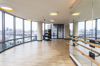 A spacious dance studio with mirrors on the wall and wooden floors.