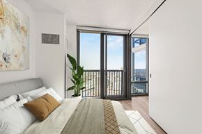 Chicago apartment for rent - A bedroom with a large bed and a view of the city through the window at Kingsbury Plaza, Illinois, 60654