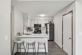 A kitchen with white countertops and bar stools.