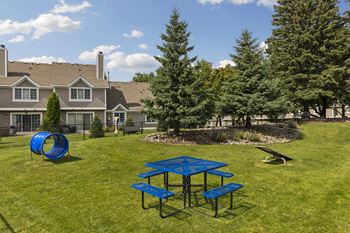 A blue picnic table is in the middle of a grassy area.