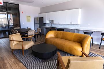 Chicago apartment for rent - A yellow sofa sits in a living room with a black coffee table in front of it.