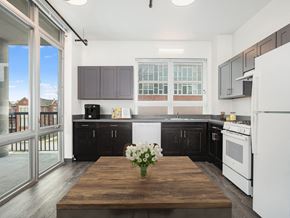 Chicago apartment for rent - a kitchen with black cabinets and white appliances and a wooden table