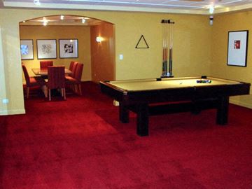 Chicago condo for rent - A pool table with a red carpet and a few chairs.