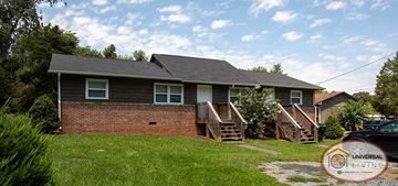 Johnson City apartment for rent - A house with a brick wall and a grey roof with a Universal Living logo in the corner.