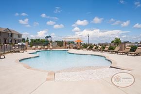 Johnson City townhouse for rent - a pool with chairs and umbrellas and a building in the background
